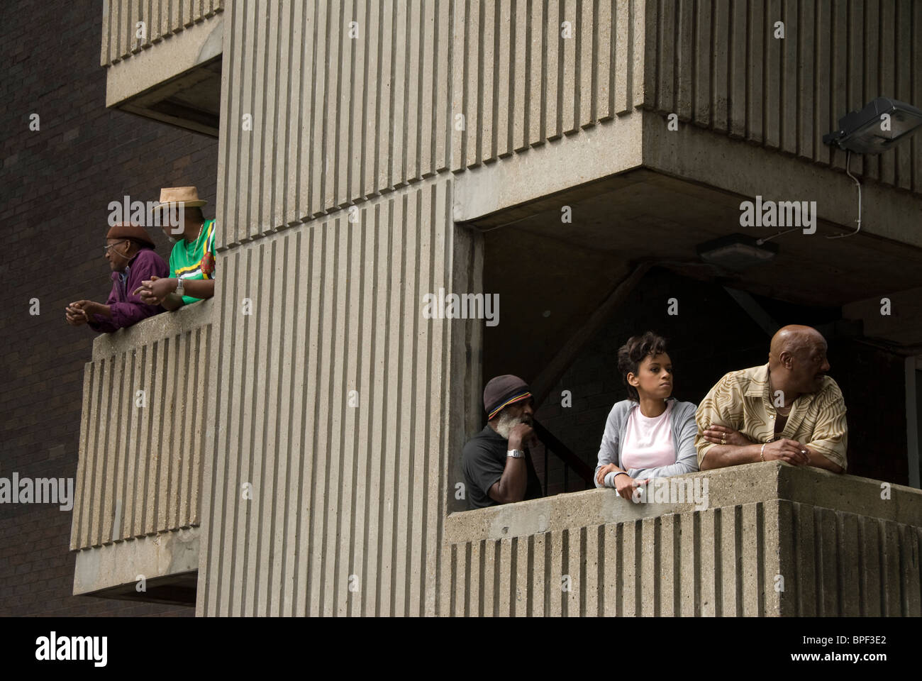 Residents in West London housing estate on their balconies watching Notting hill carnival going by. Stock Photo