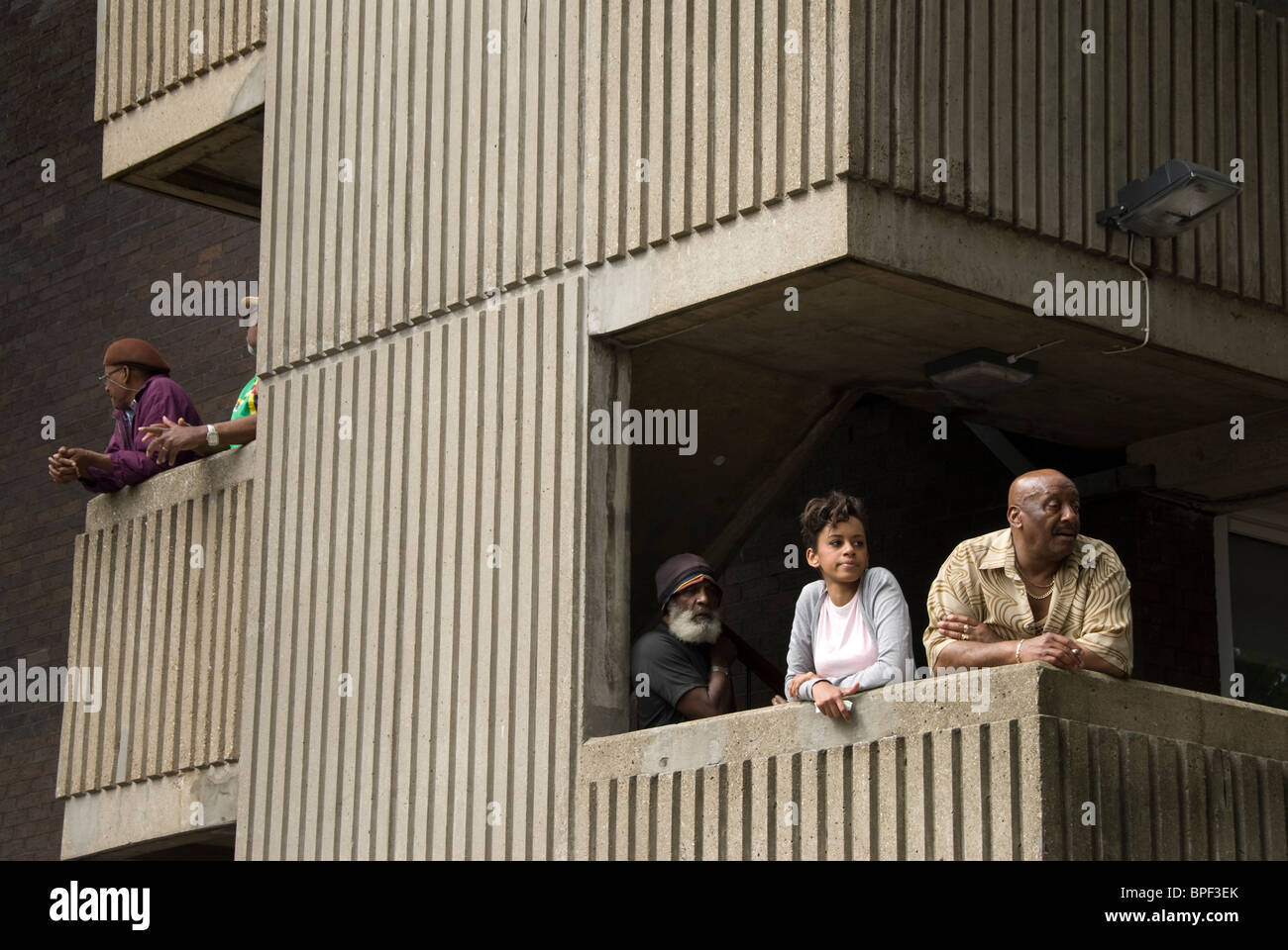 Residents in West London housing estate on their balconies watching Notting hill carnival going by. Stock Photo