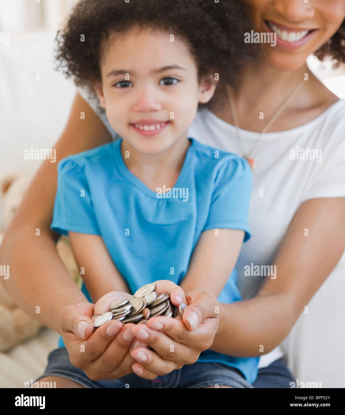 Mother and daughter cupping coins in hands Stock Photo