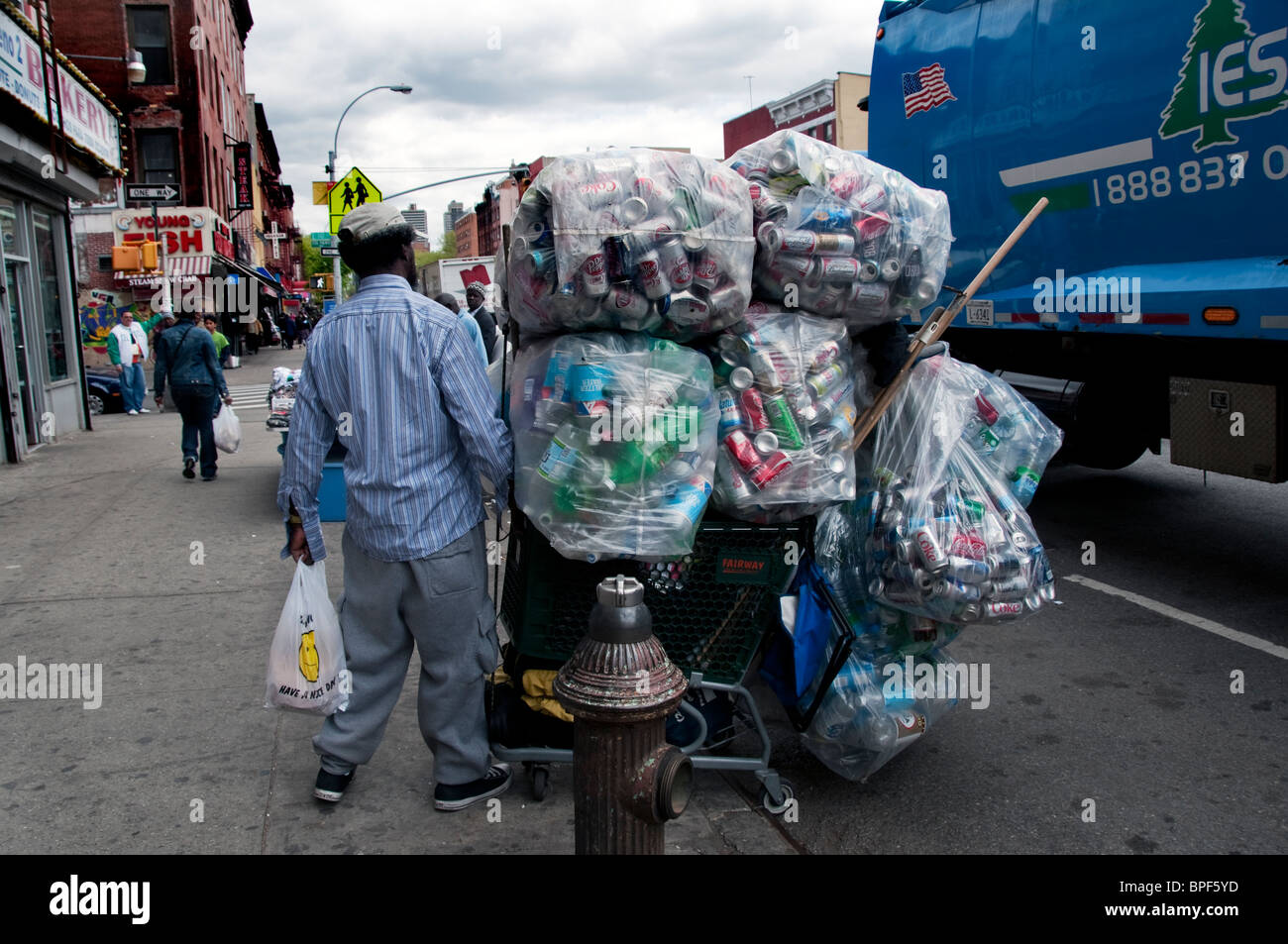 Homeless man in East Harlem collecting cans and bottles to recycle and