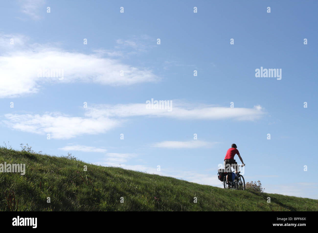 Man cycling on top of a grass ledge Stock Photo