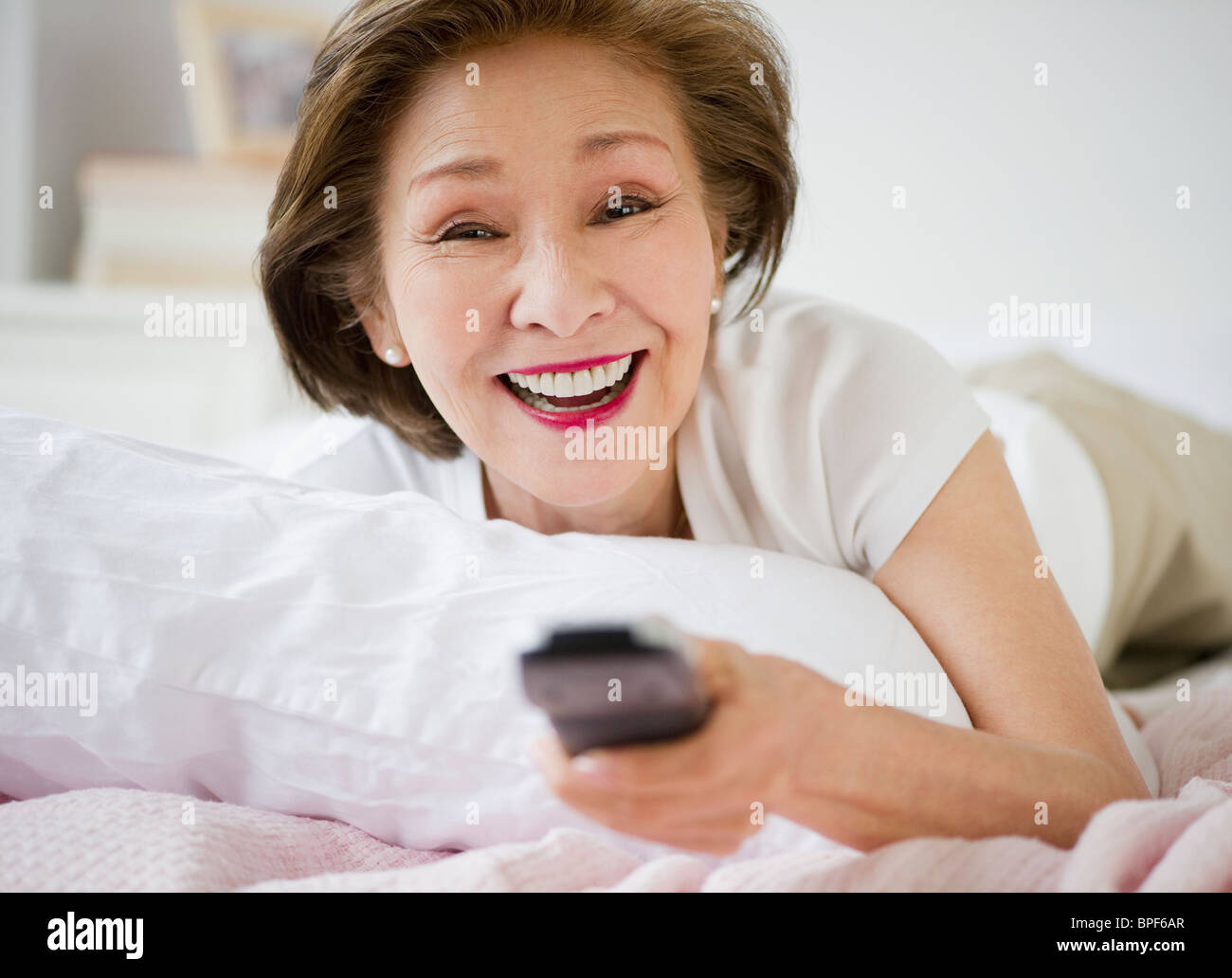 Japanese woman watching television in bed Stock Photo
