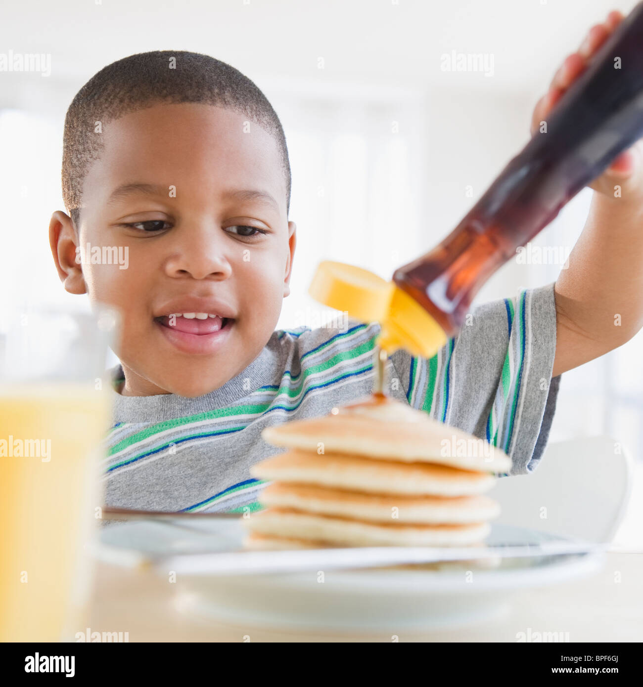 African American boy pouring syrup on pancakes Stock Photo Alamy