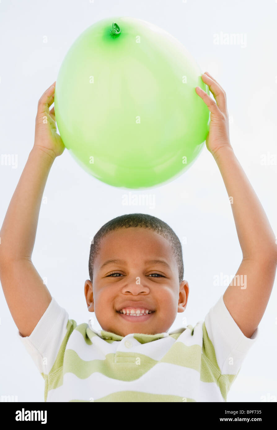 African American boy holding balloon above head Stock Photo