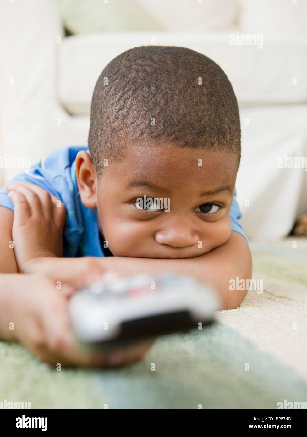 African American boy laying on floor watching television Stock Photo