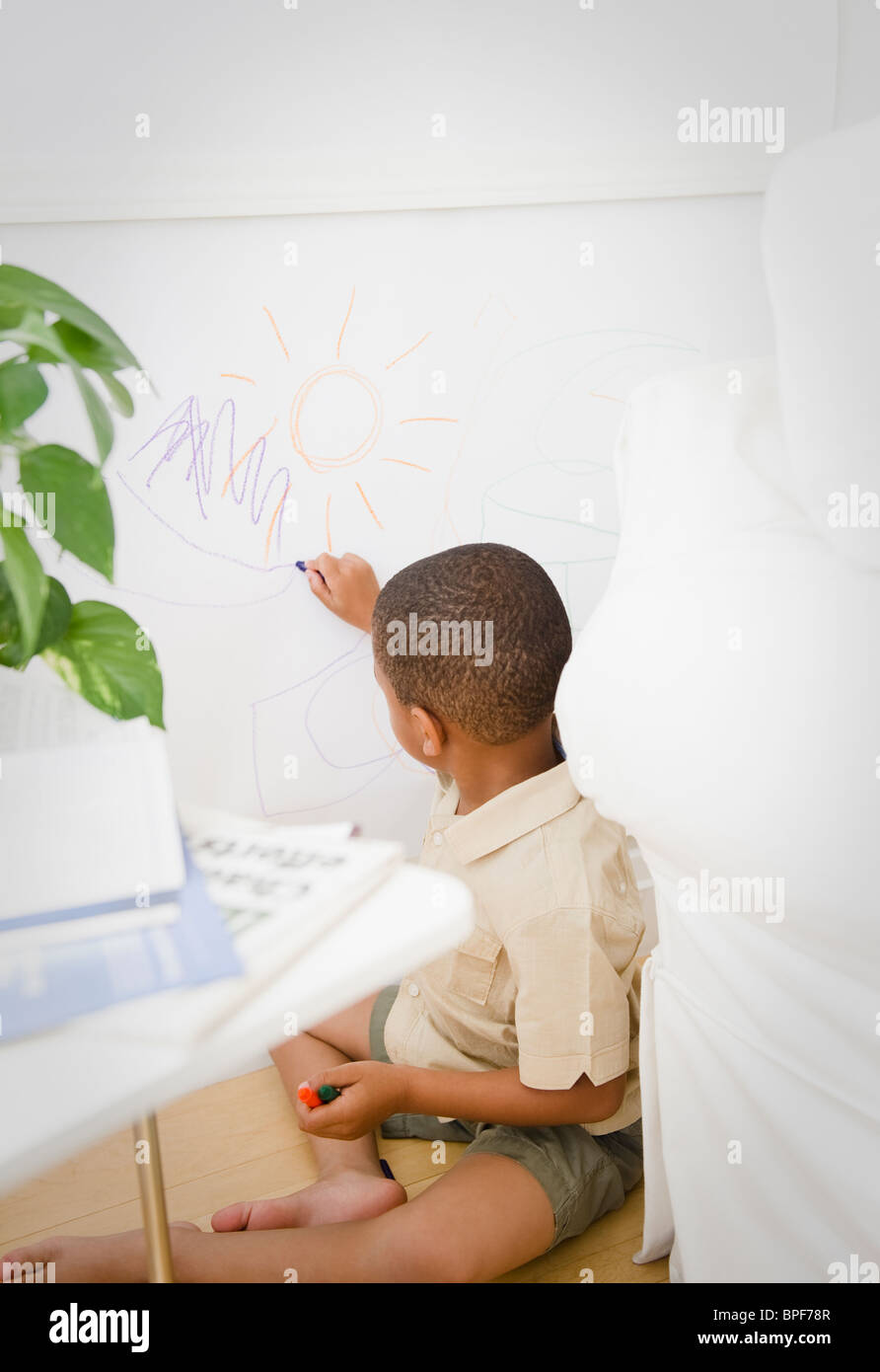 African American boy drawing on wall with crayon Stock Photo