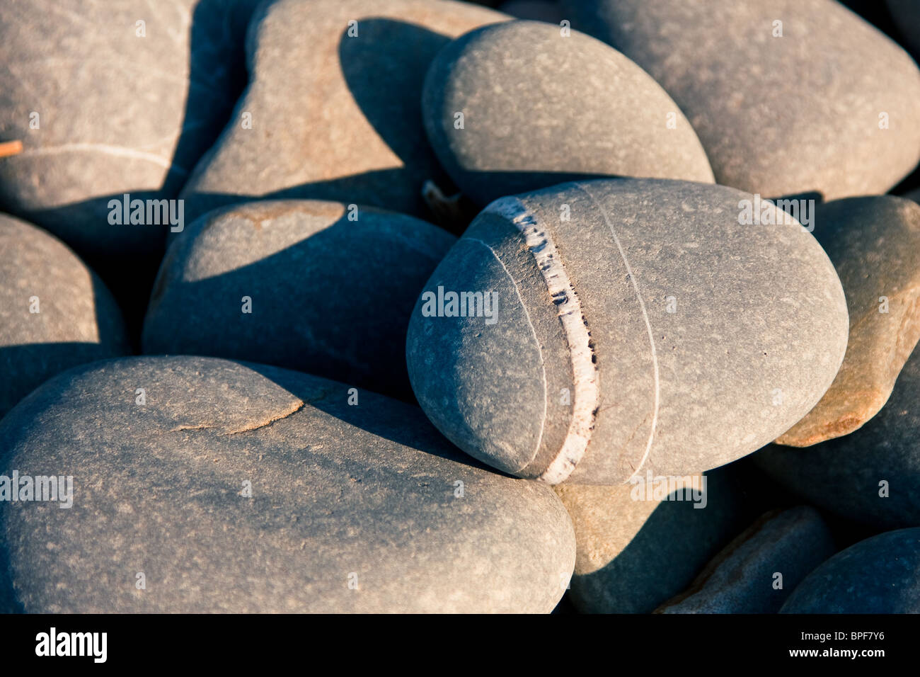 Close up of pebbles on a beach taken at sun set to give a lovely warm glow. Stock Photo