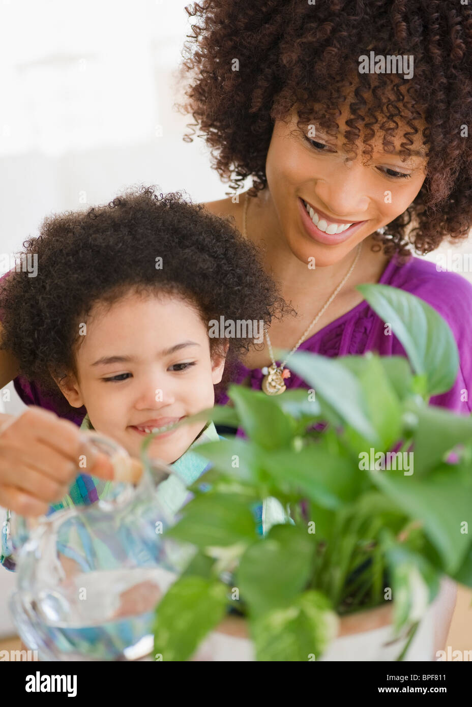Mother and daughter watering potted plant Stock Photo