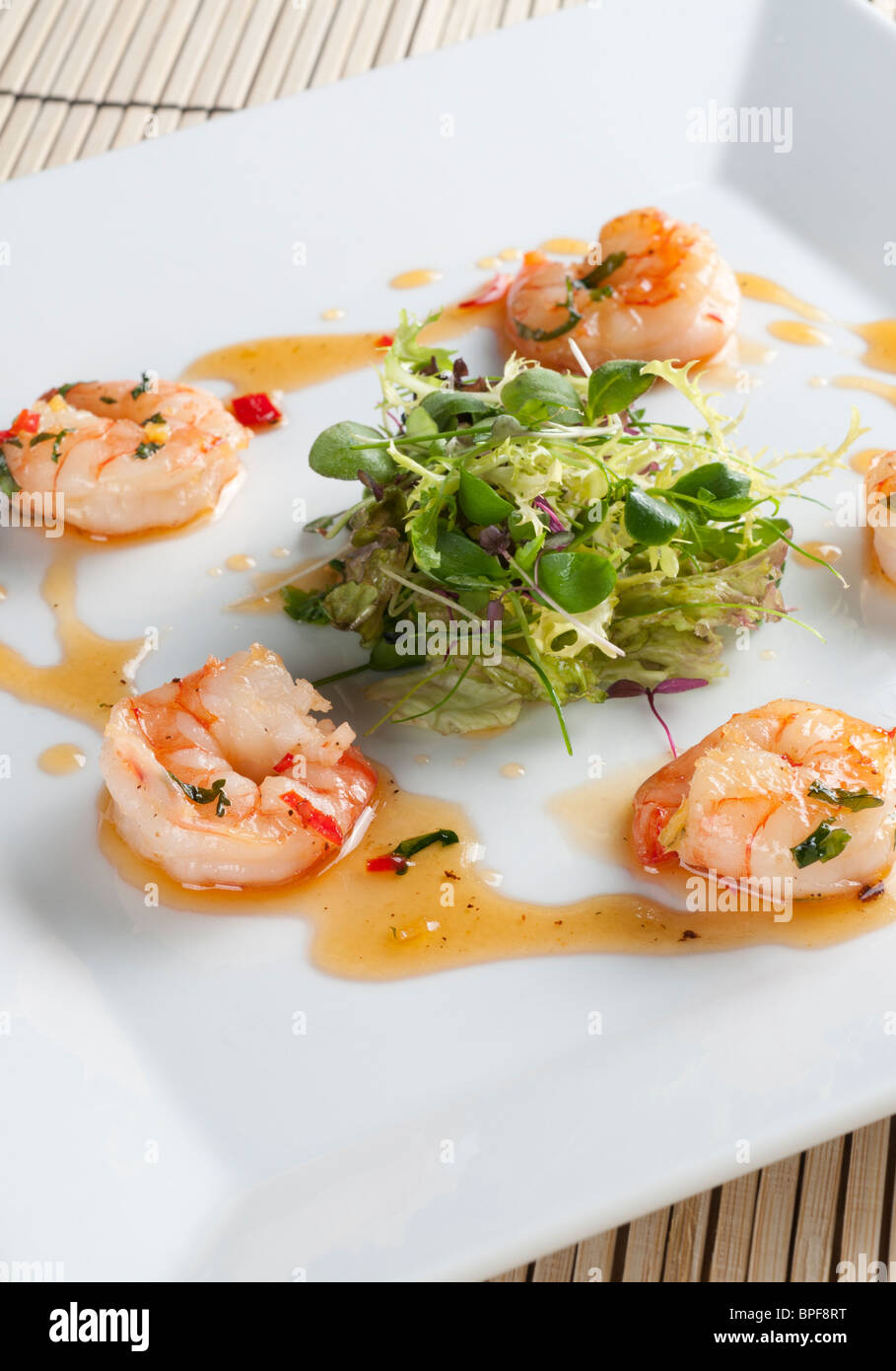 Sauté prawns with chill, ginger and coriander with a nest of baby leaf salad Stock Photo