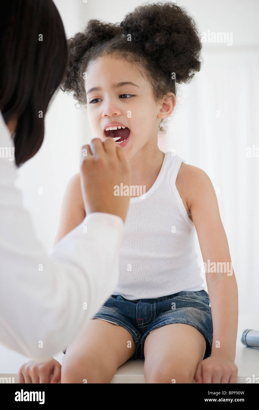 Pediatrician with tongue depressor examining patient Stock Photo