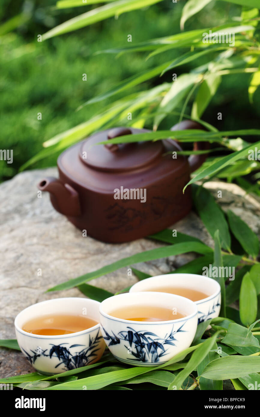 Teapot and cups on stone with bamboo leaves. Stock Photo