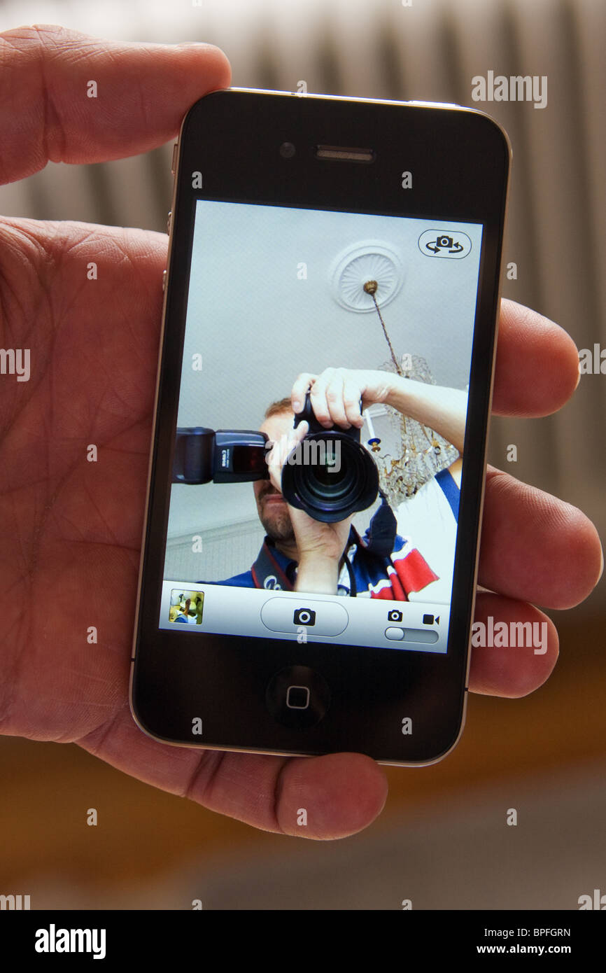 iPhone 4 in the palm of a hand, showing a live image of the photographer taking a photo of it. Stock Photo