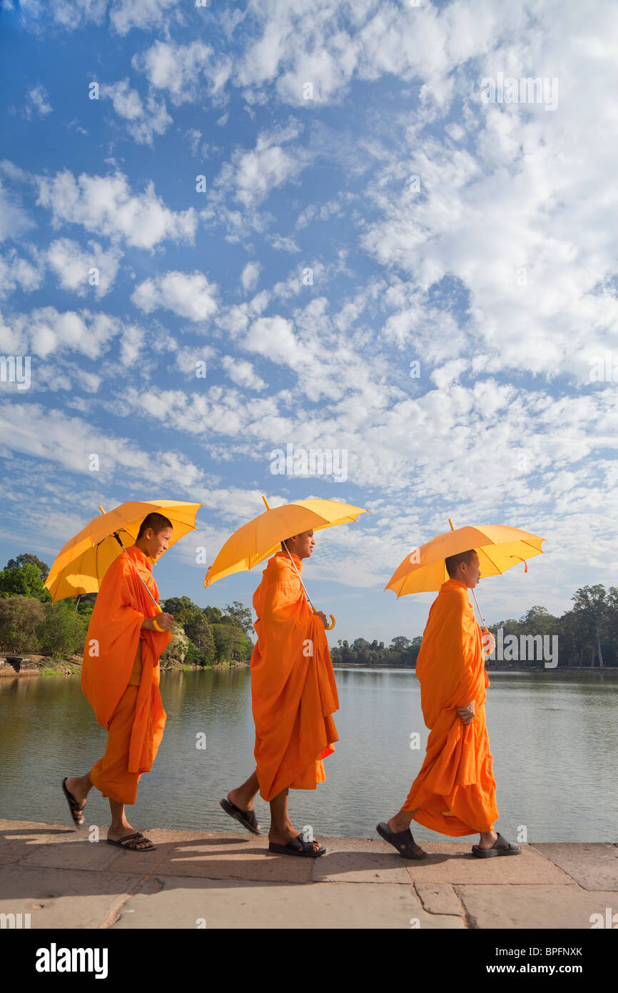 Three Monks by the moat surrounding Angkor Wat Temple complex, Siem Reap, Cambodia, South East Asia Stock Photo
