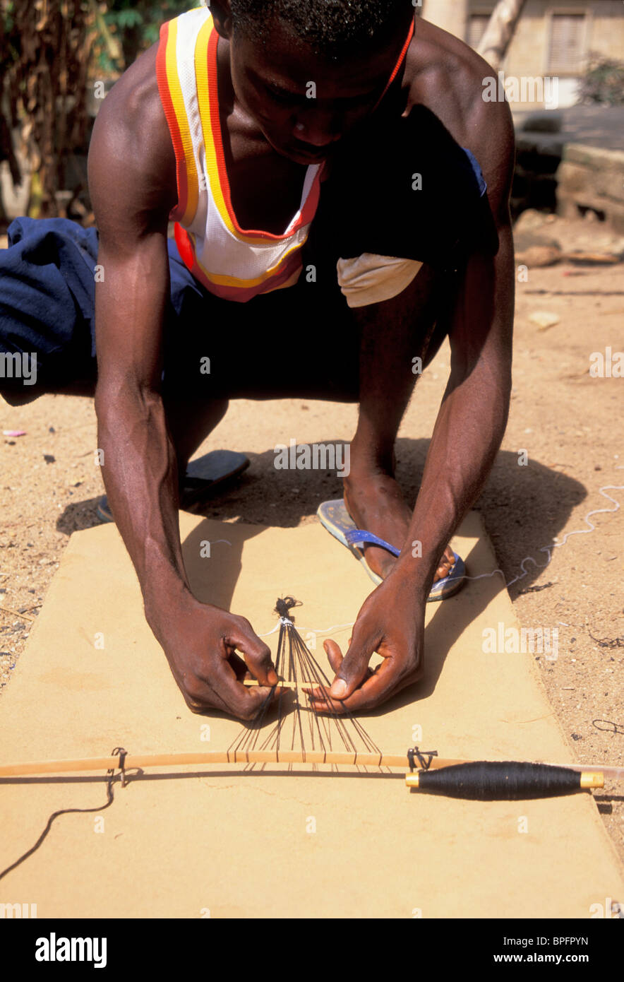 Boy weaving kente cloth on an Ashante table loom, Ghana Stock Photo