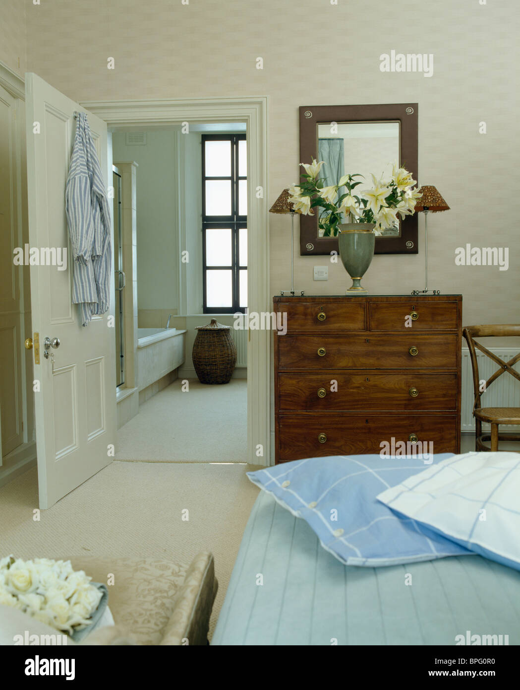 Pale blue cushions on bed in townhouse bedroom with antique chest-of