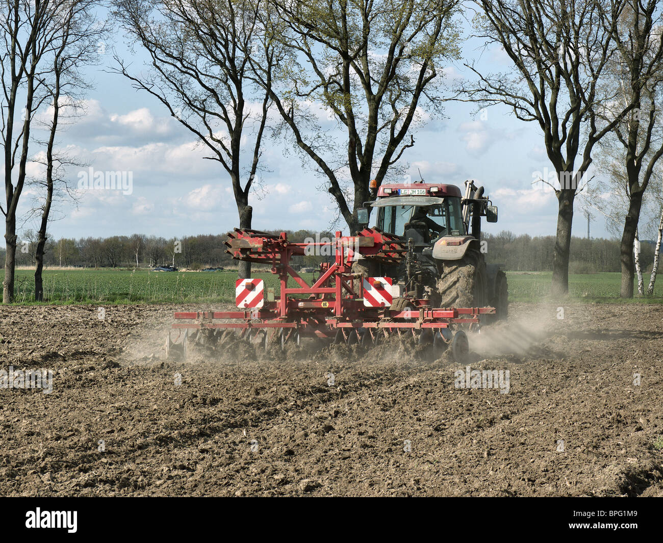 Farmer cultivating his acre with his tractor-drawn harrow near Barum, Elbmarsch, Germany. Stock Photo