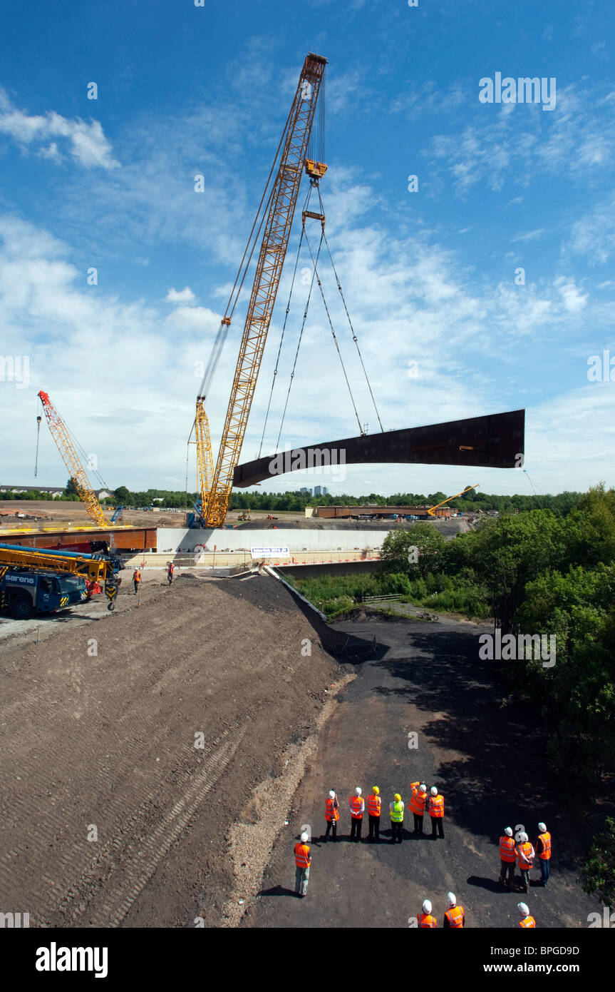 Construction workers move a steel bridge by crane into position over