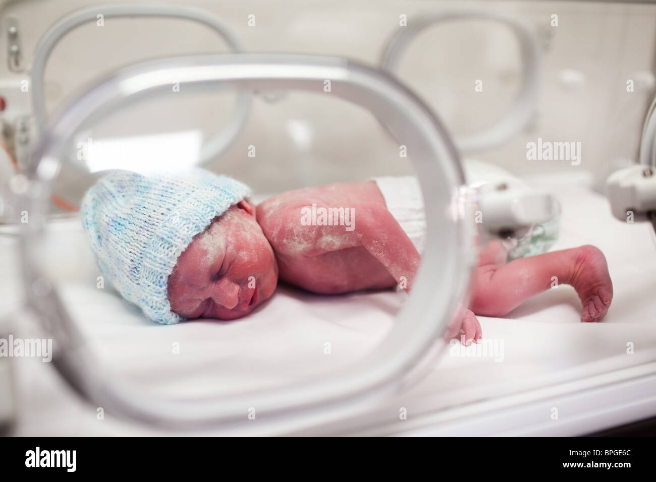 Newborn baby boy covered in vertix in incubator Stock Photo