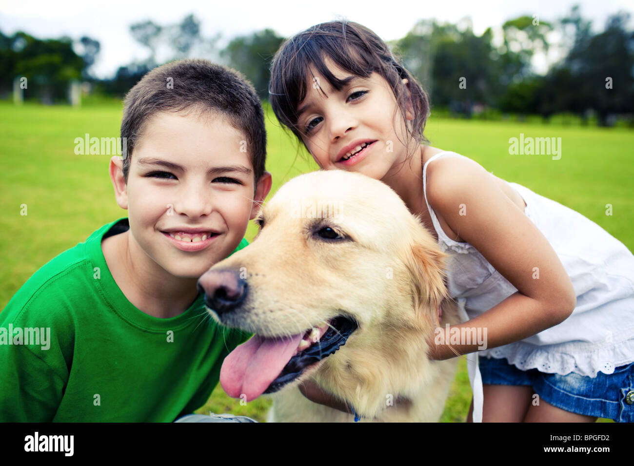 Young boy and girl hugging a golden retriever outdoors Stock Photo Alamy