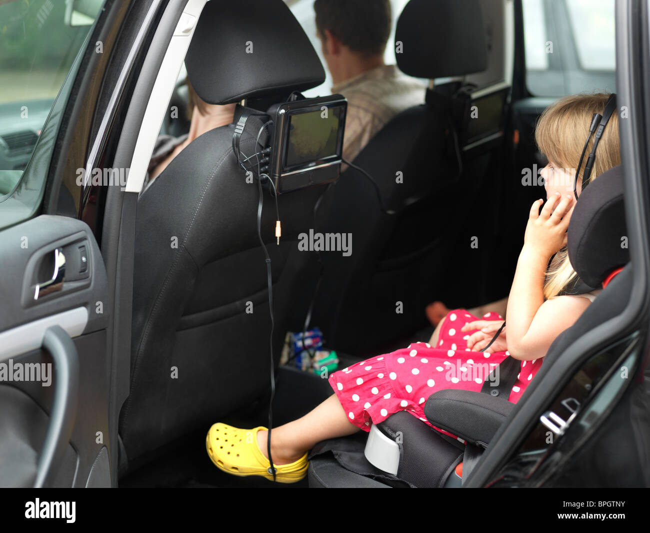Girl In Childs Car Seat In The Back Of Car Watching a DVD England Stock Photo