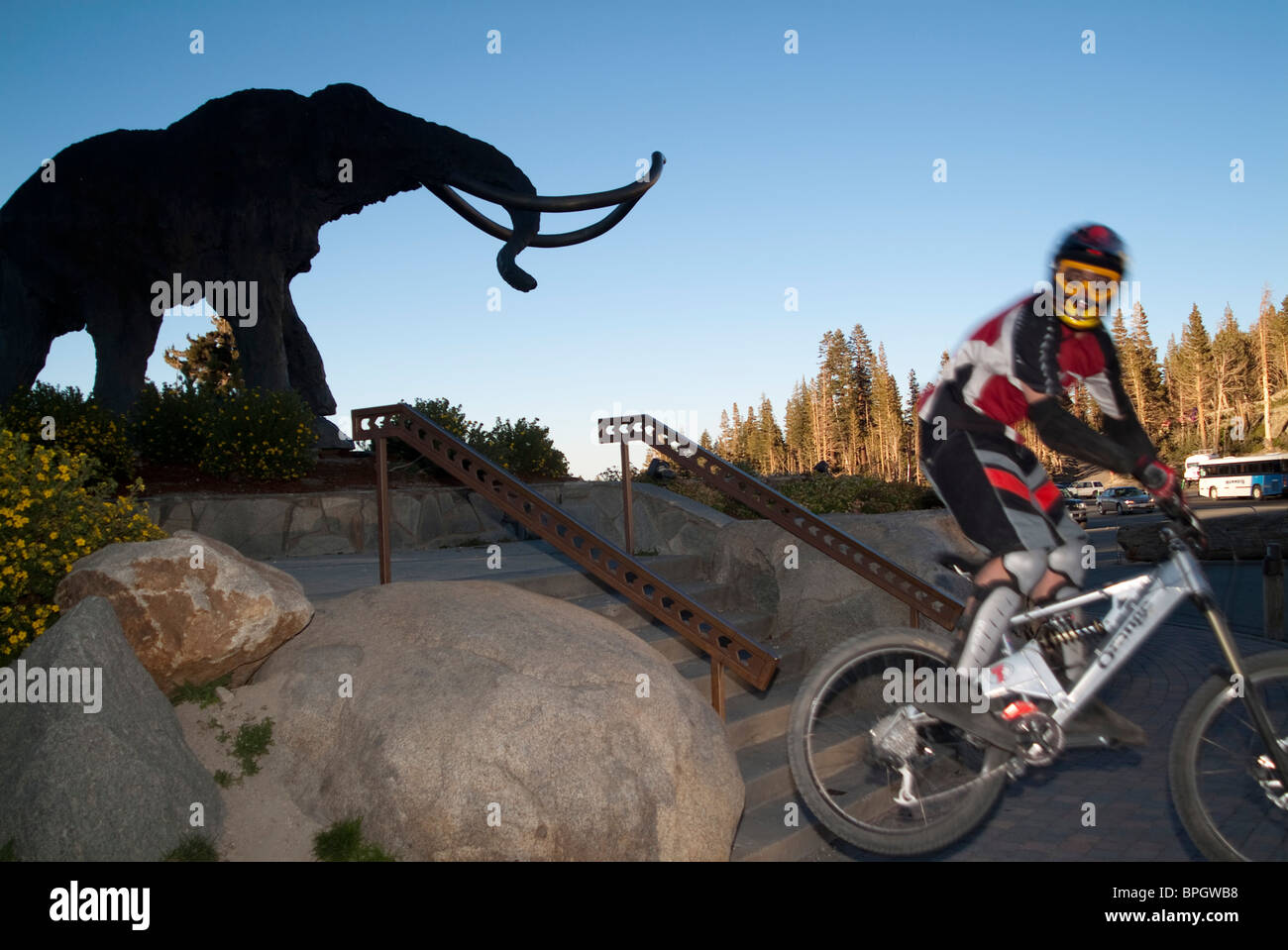 Man riding down rocks with elephant statue in background. Stock Photo