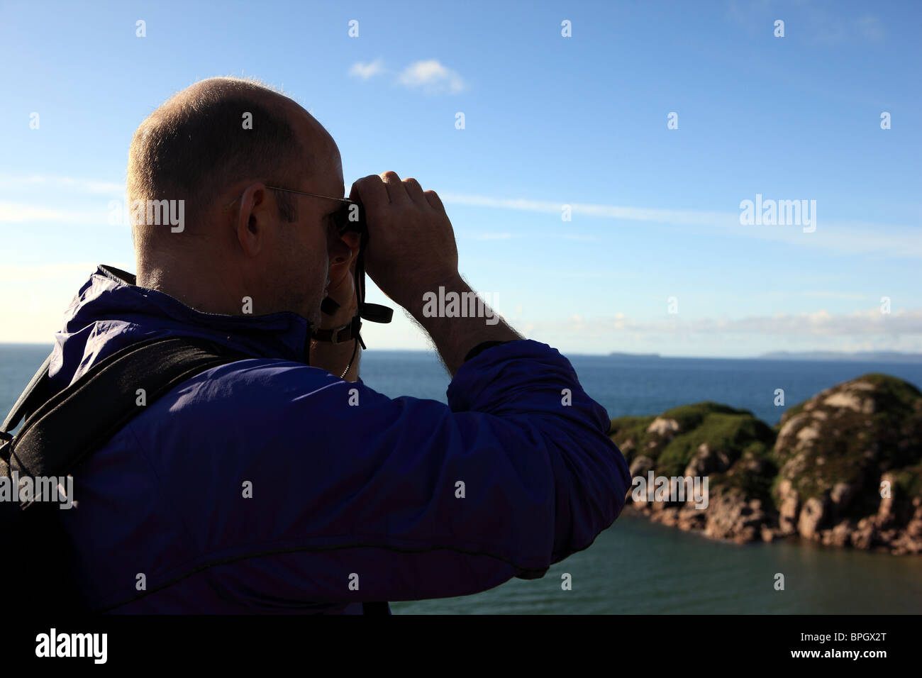 Man looking out to sea through binoculars Stock Photo - Alamy