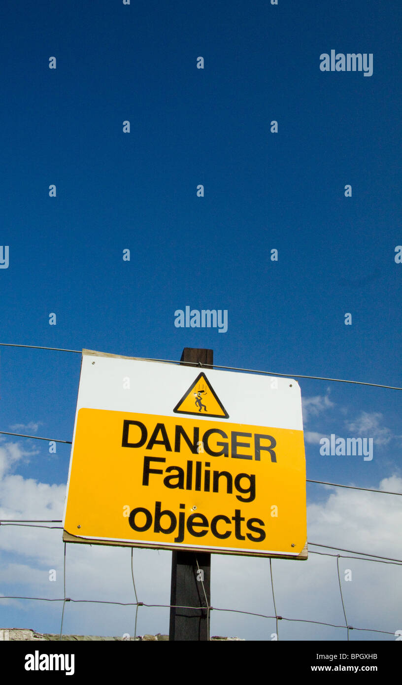 A warning sign drawing attention to the danger of falling objects. Above the notice is nothing but sky Stock Photo