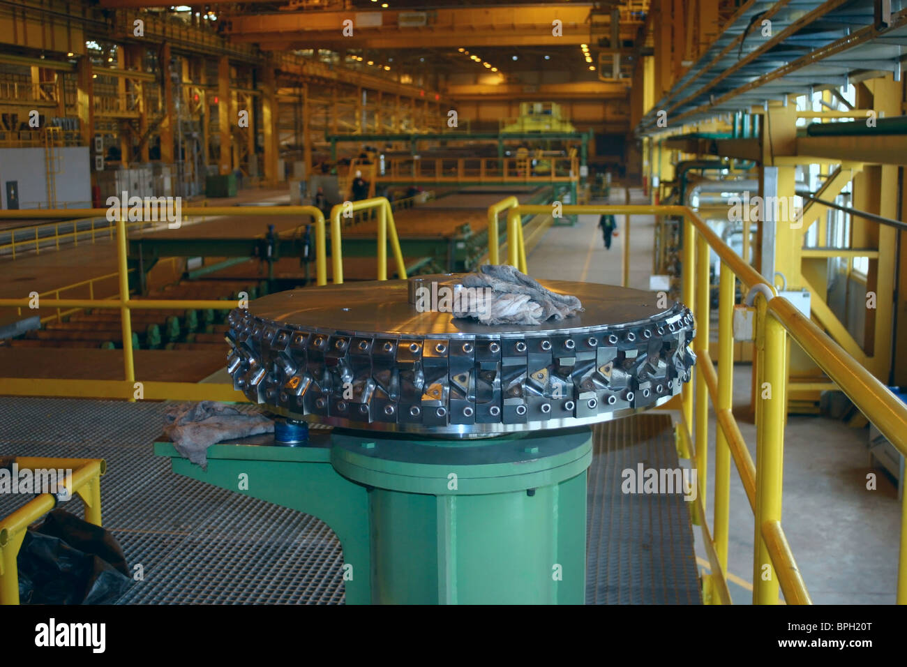 Steel gear lies on the tube. Rolled sheet production behind it. Stock Photo