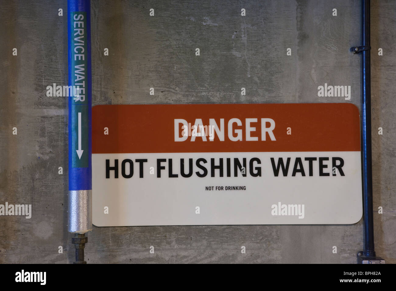Hot flushing water pipe with warning sign in a sewage treatment plant