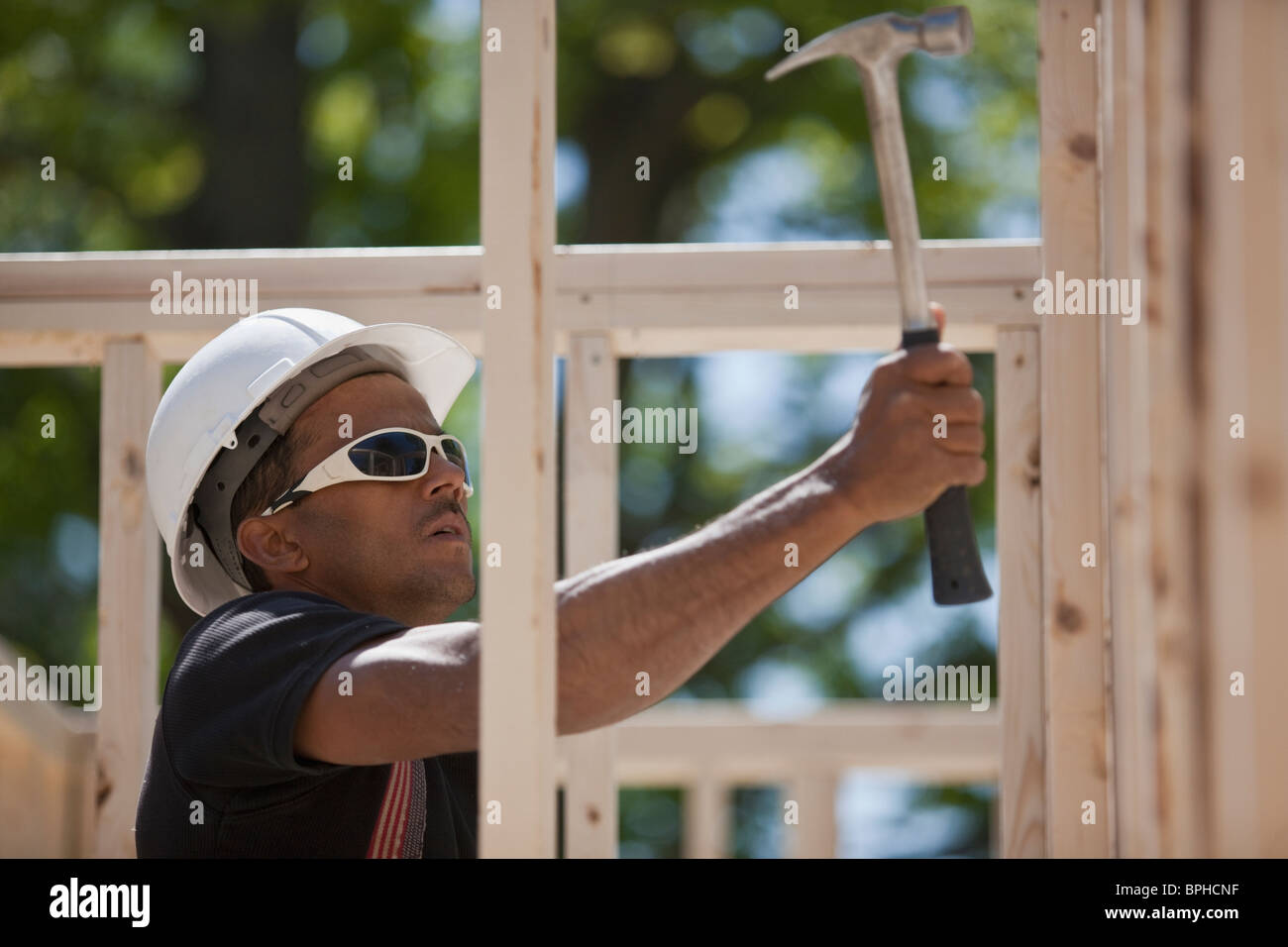Carpenter nailing on wood framing at a construction site Stock Photo