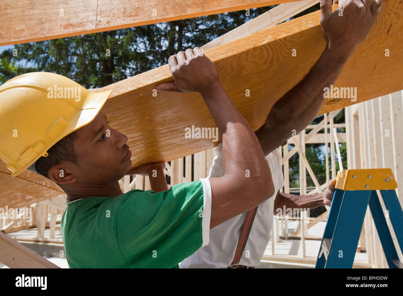 Carpenters lifting a laminated beam at a construction site Stock Photo