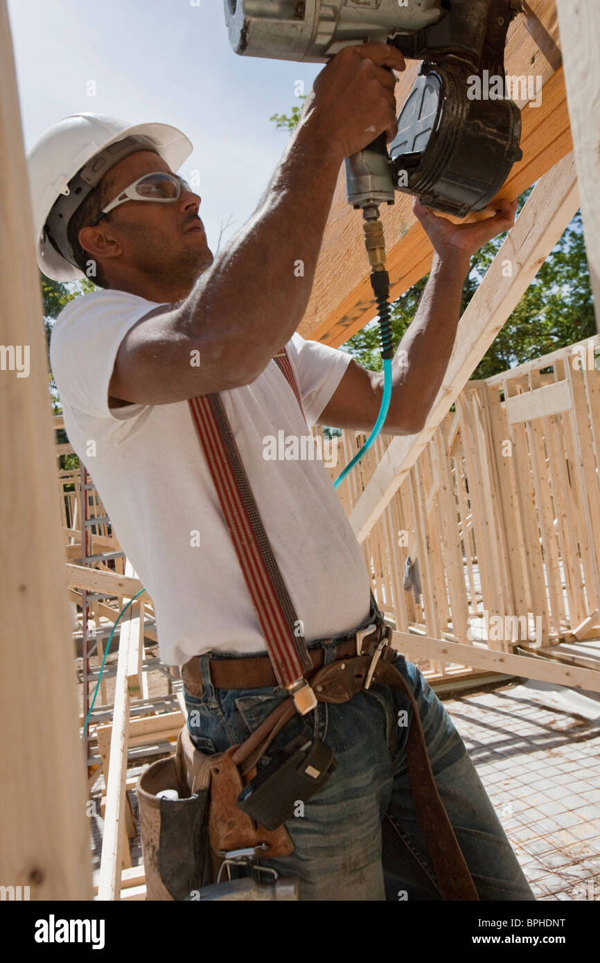 Carpenter using a nail gun at a construction site Stock Photo Alamy