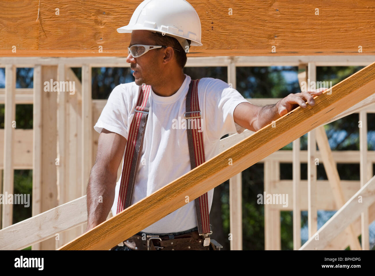 Carpenter lifting a laminated beam at a construction site Stock Photo
