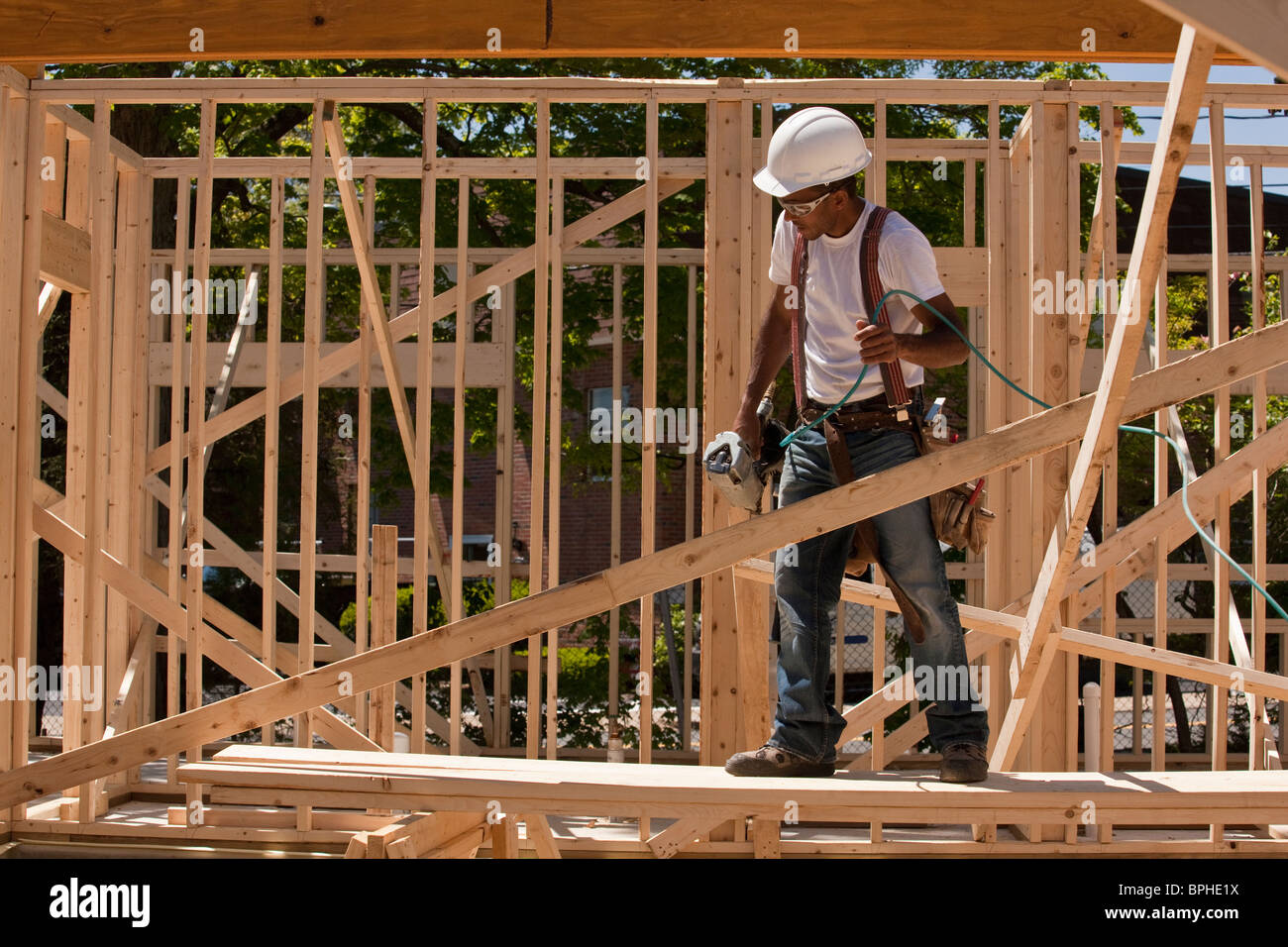Carpenter standing at a construction site holding a nail gun Stock