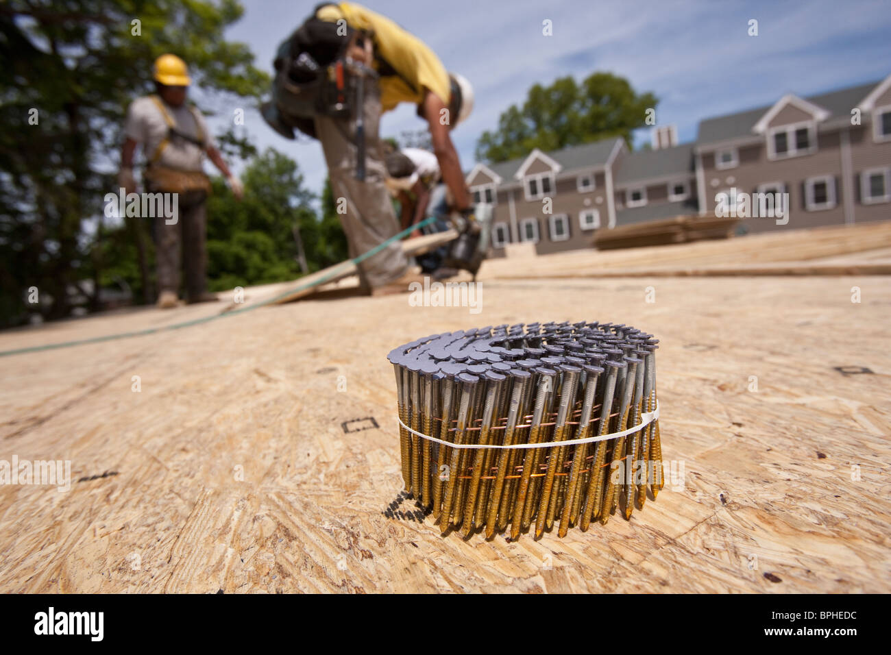 Bundle of nails with a carpenter using nail gun in the background Stock