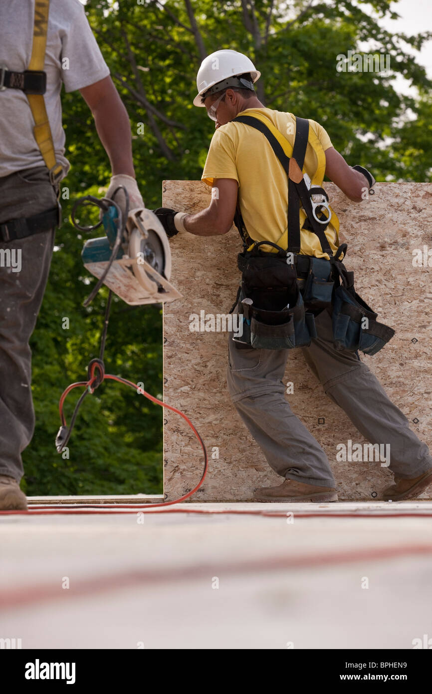Carpenters lifting particle board and holding circular saw Stock Photo
