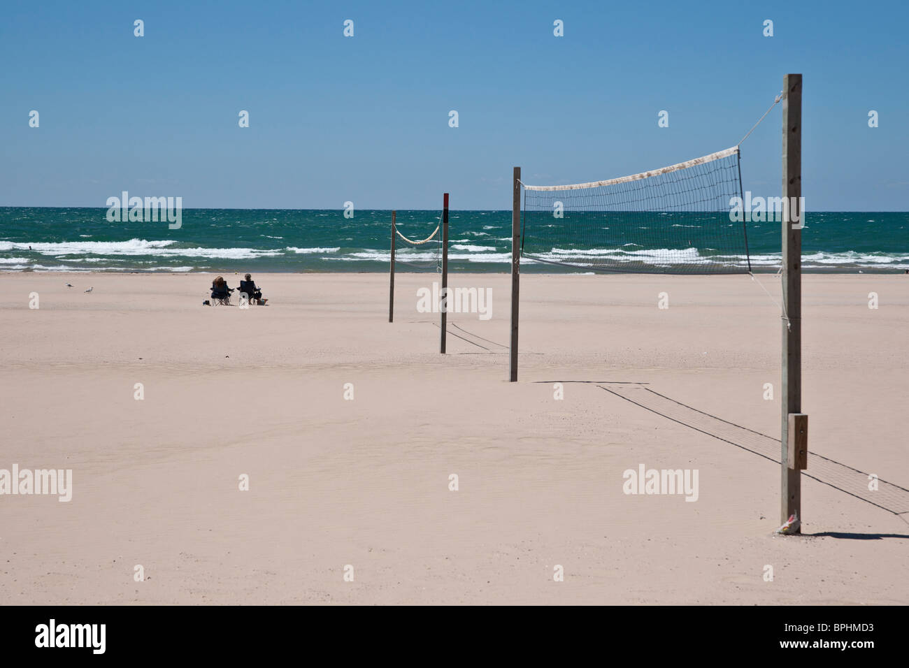 Volleyball nets on Ludington Lake Michigan beach and two lonely women relaxing in the chairs in
