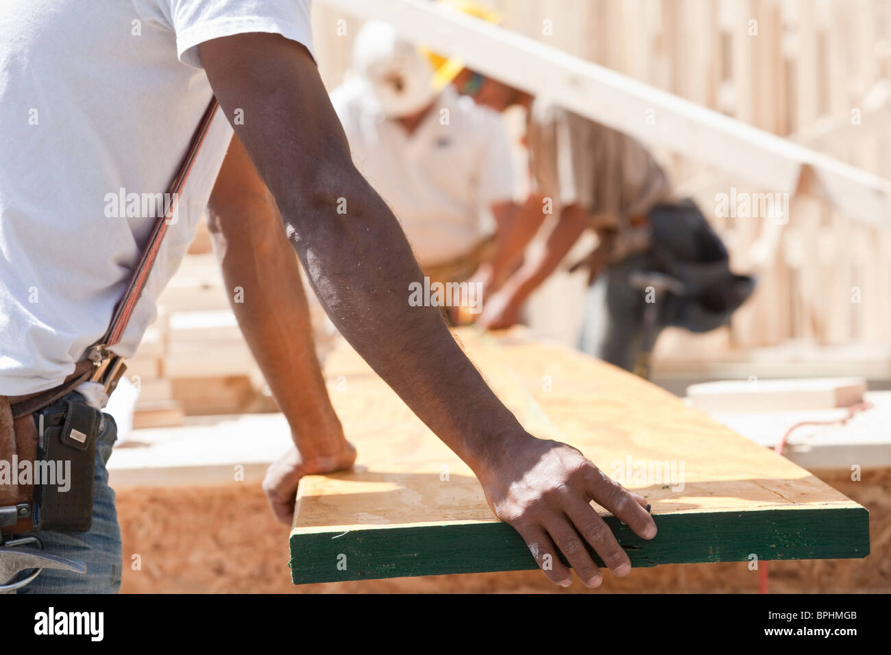 Carpenters holding a plank at a construction site Stock Photo Alamy