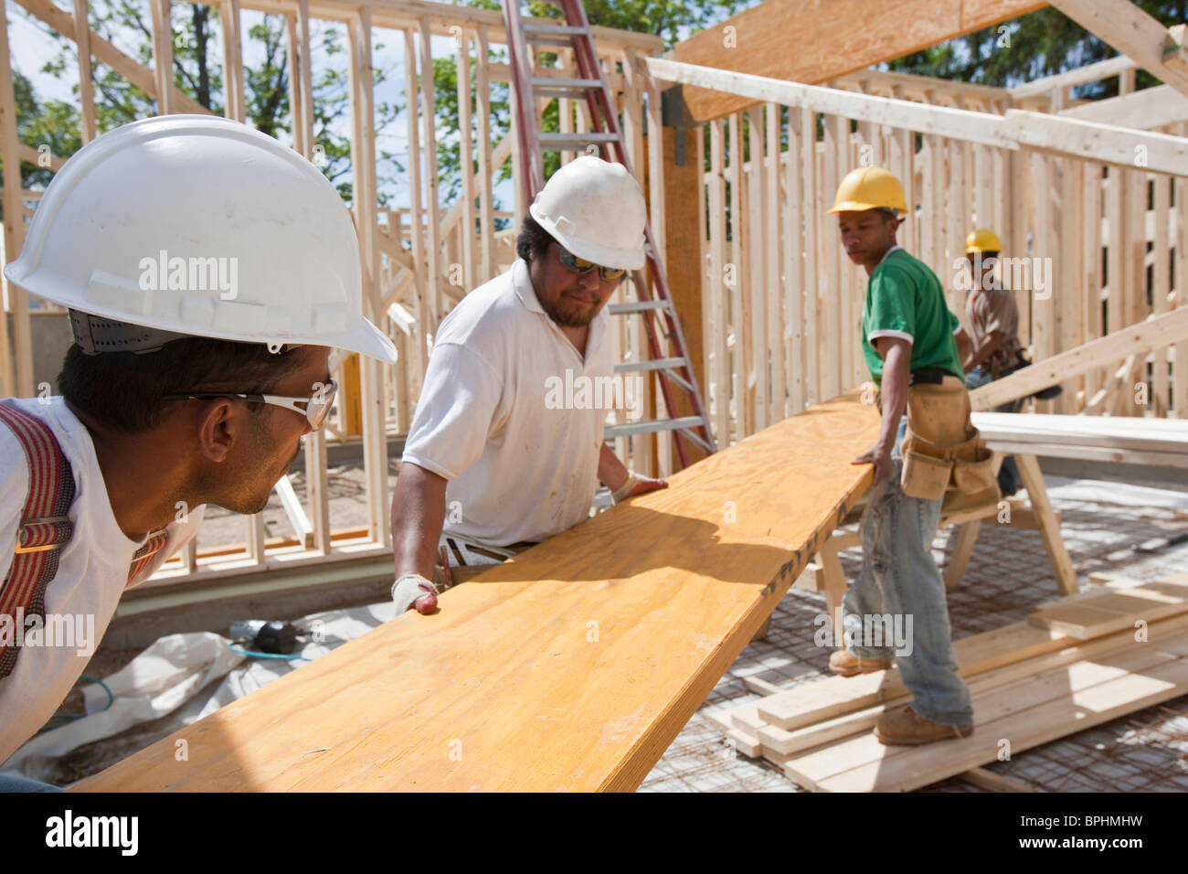 Carpenters lifting a laminated beam at a construction site Stock Photo