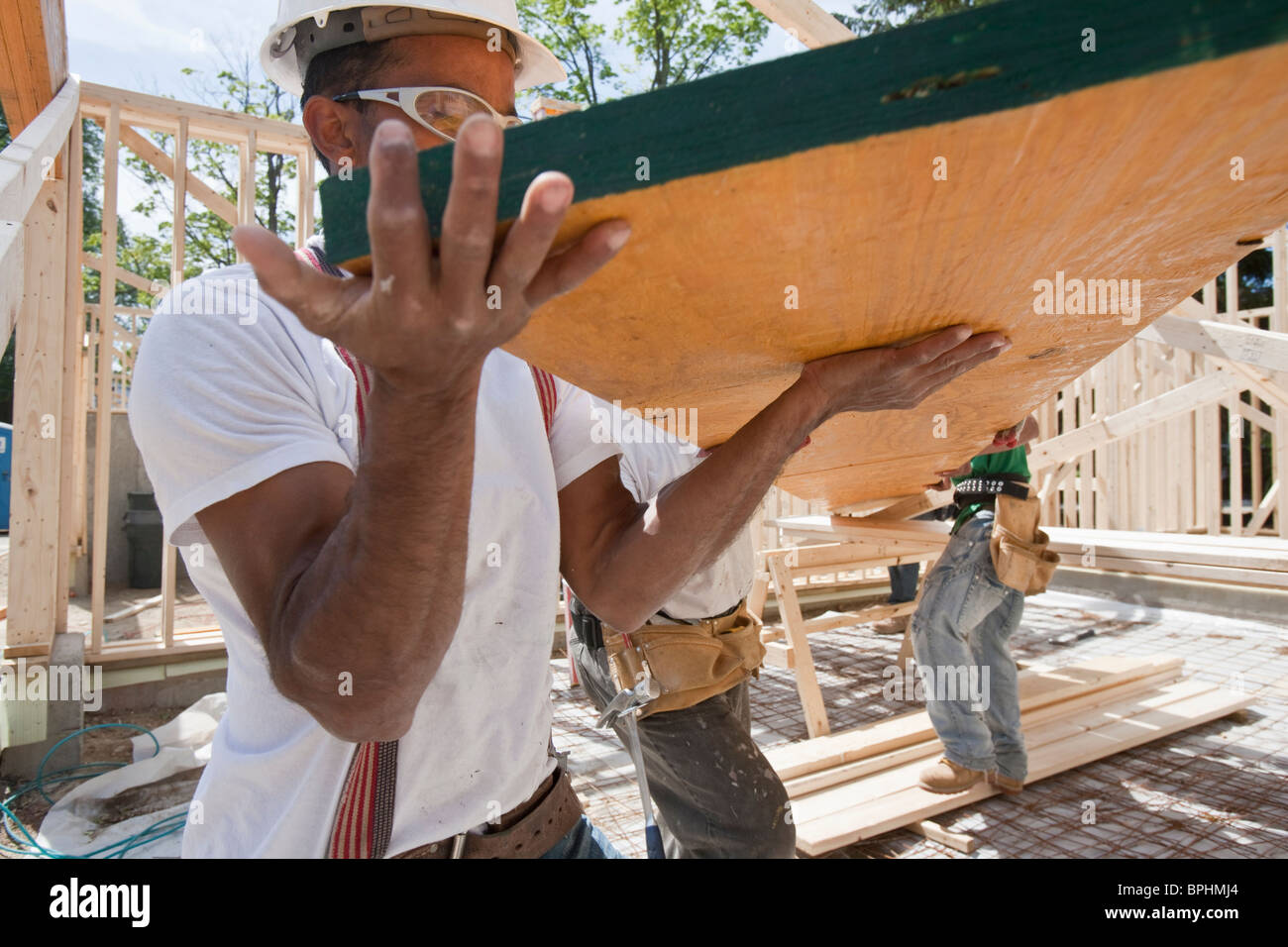 Carpenters lifting a laminated beam at a construction site Stock Photo