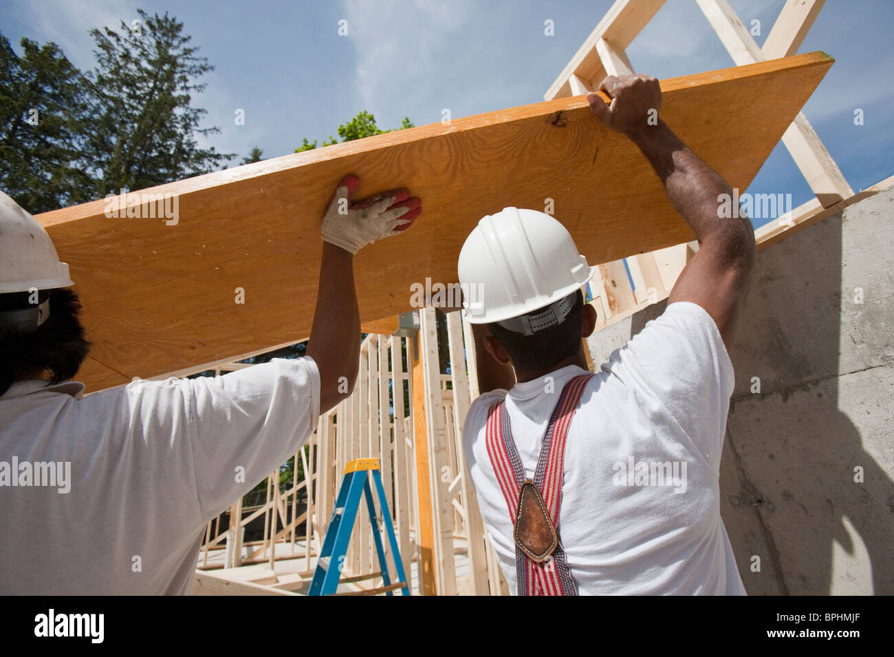 Carpenters lifting a laminated beam at a construction site Stock Photo