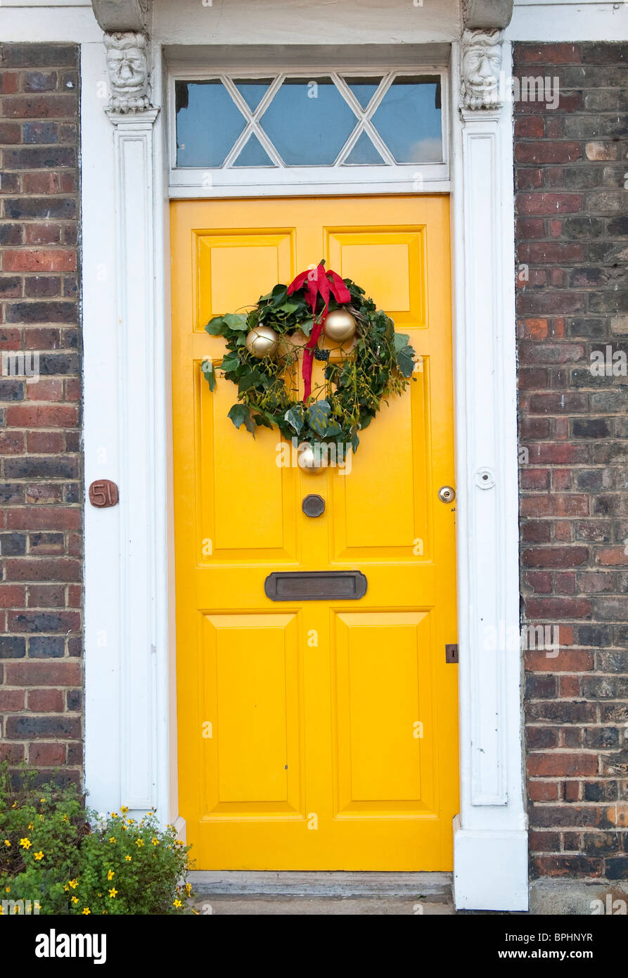 Yellow door decorated with a  Christmas wreath Stock Photo