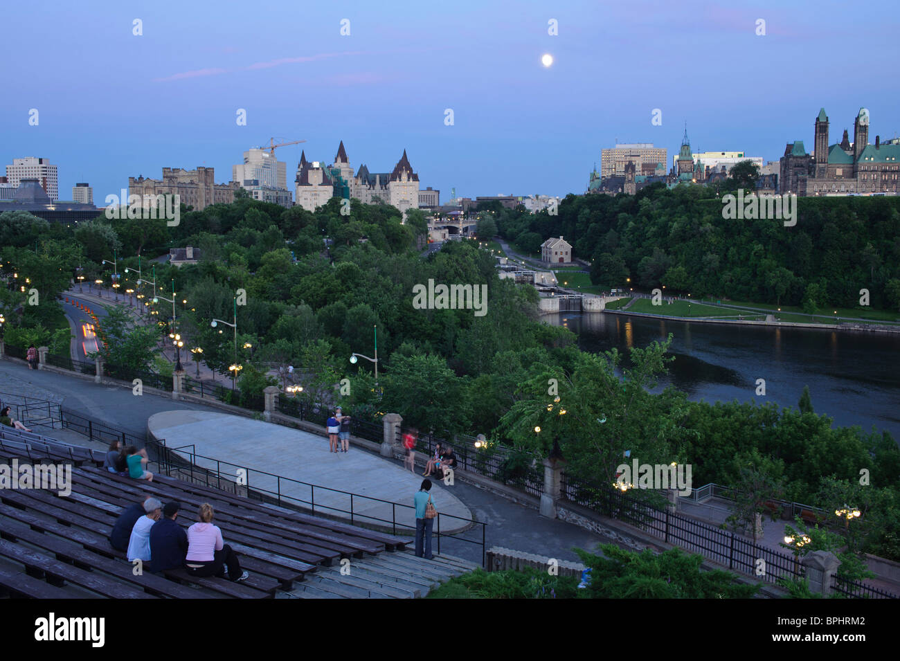 People at Astrolabe Theatre at Nepean Point, Chateau Laurier, Rideau Canal Locks, Bytown Museum, Parliament Hill and Ottawa River at dusk, Nepean Point Ottawa Ontario Canada Stock Photo