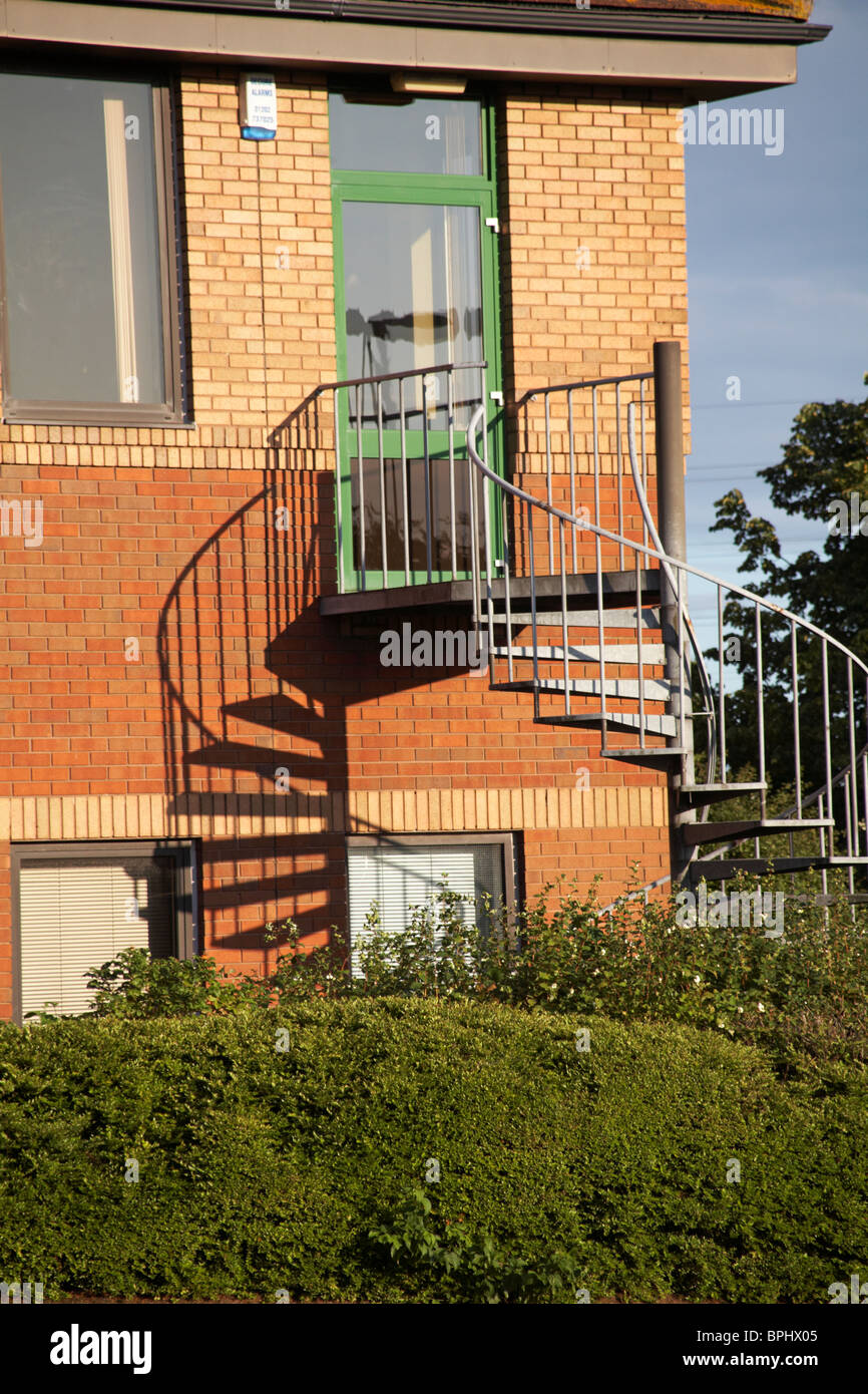 fire escape spiral staircase with shadows on building in Poole Stock Photo