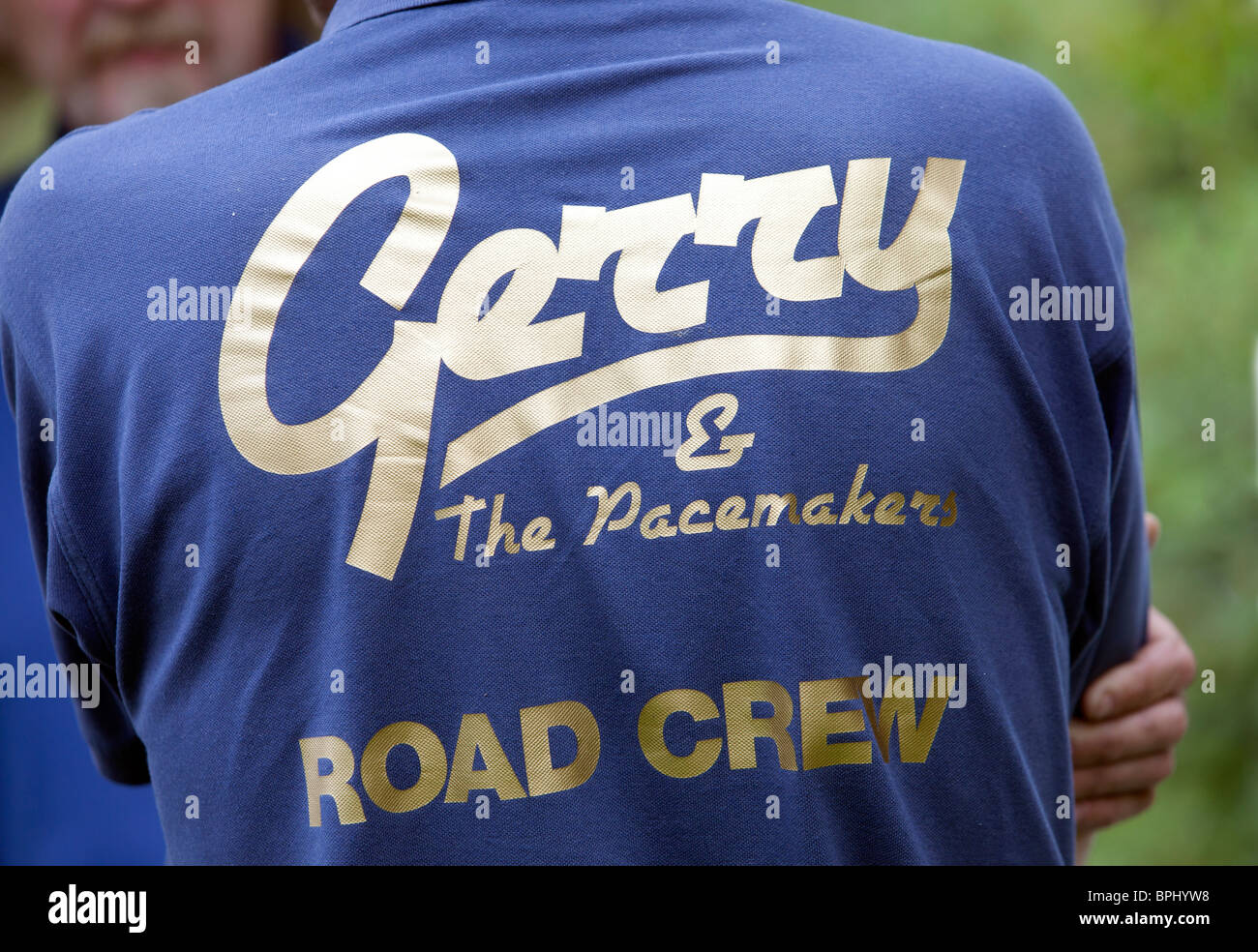 A member of the gerry and the Pacemakers road crew wears a gold lettered logo on the back of his shirt. Stock Photo