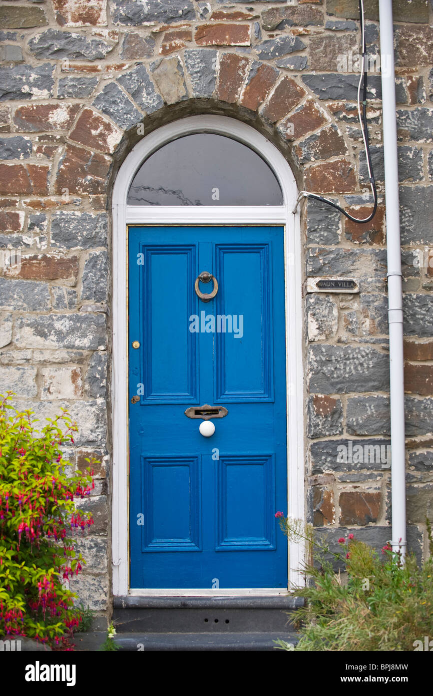 Blue painted paneled front door with glazed fanlight brass knocker letterbox and white knob of stone built house in UK Stock Photo
