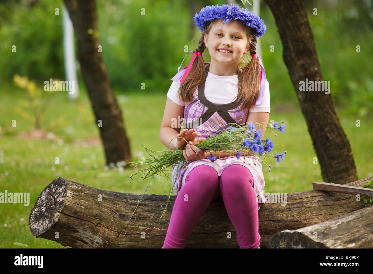 Little girl with a chaplet made from blue flowers Stock Photo