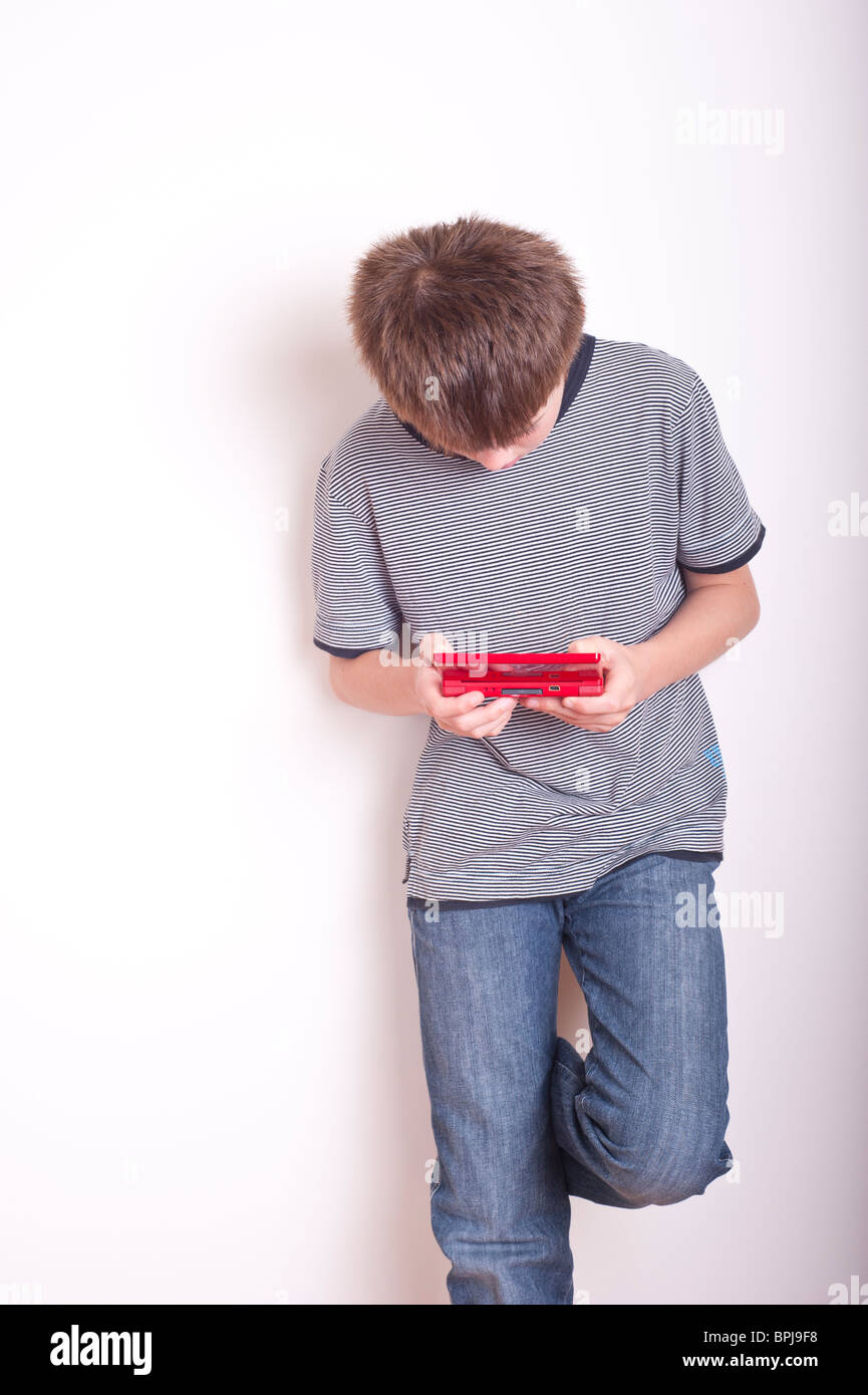 A MODEL RELEASED picture of a 10 year old boy playing with a Nintendo DS handheld games console in the studio Stock Photo