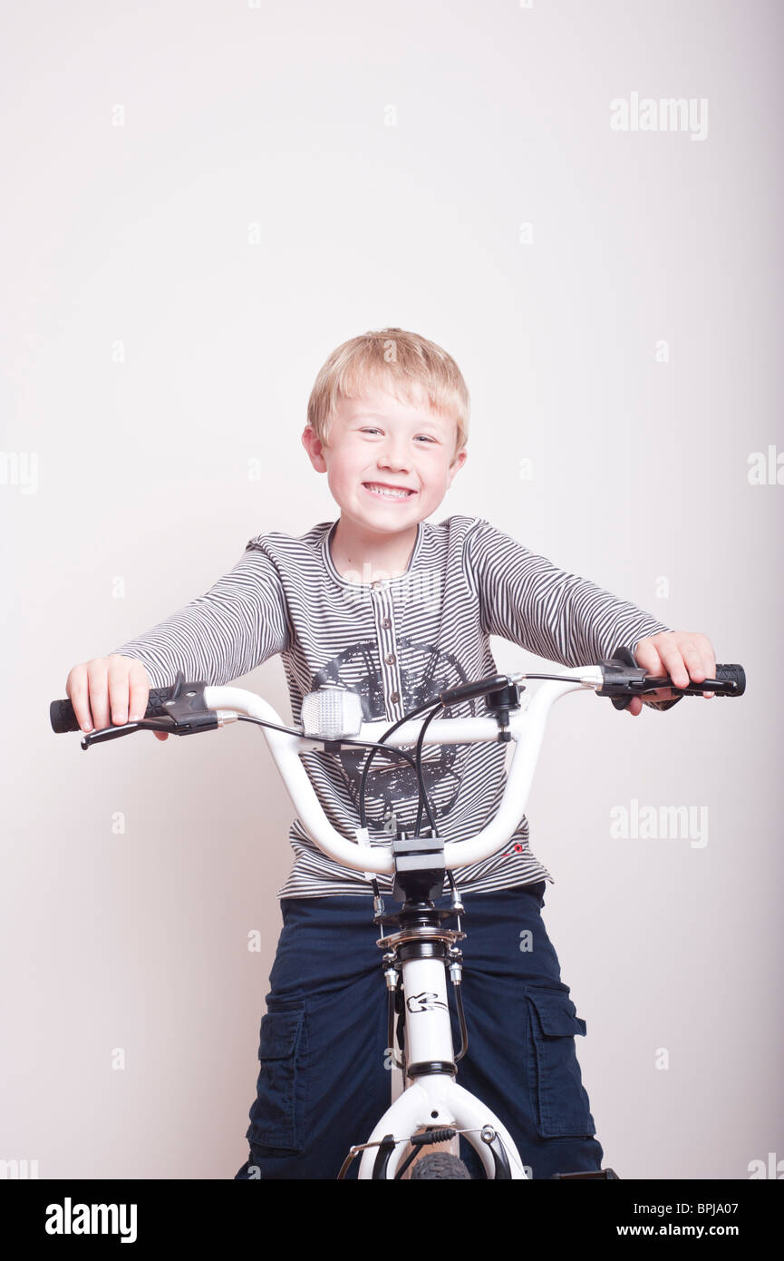 A MODEL RELEASED picture of a 6 year old boy sitting on his brand new BMX bike in the studio looking happy Stock Photo