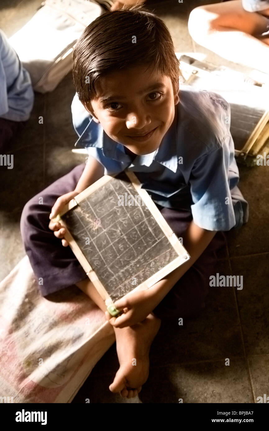 A young Indian boy holds a chalkboard during lessons at a school in Sasan in Gujarat, India. Stock Photo